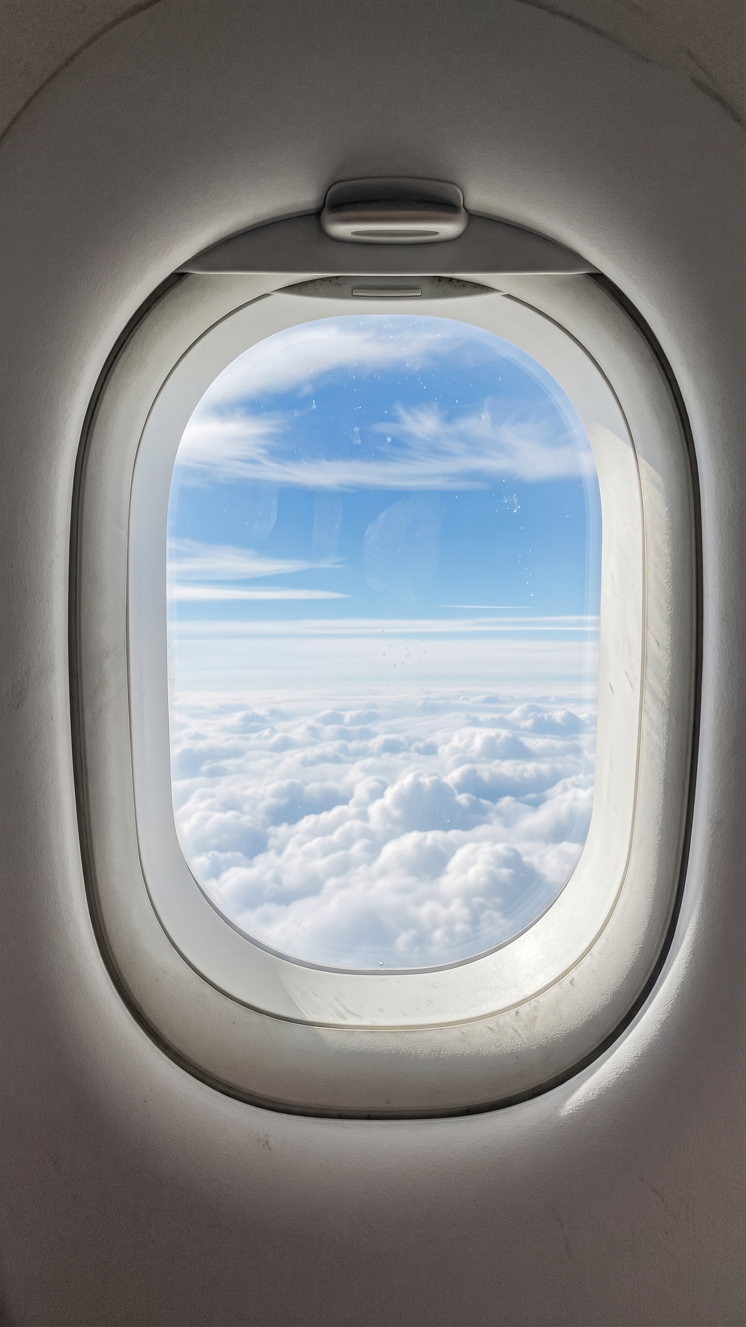 Clouds and clear blue sky seen through an aircraft window